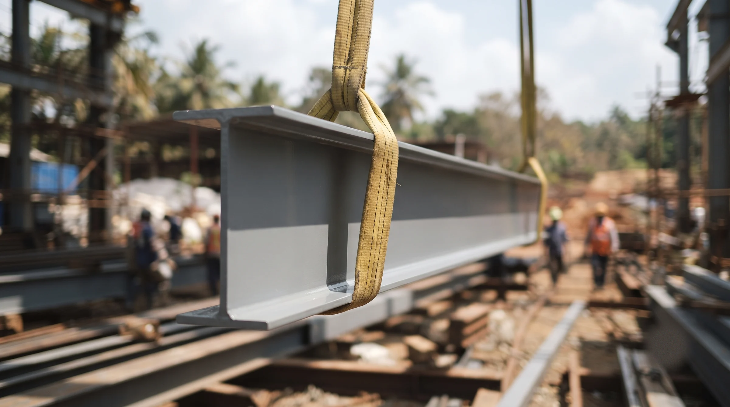 Primed structural steel beam lifted on slings