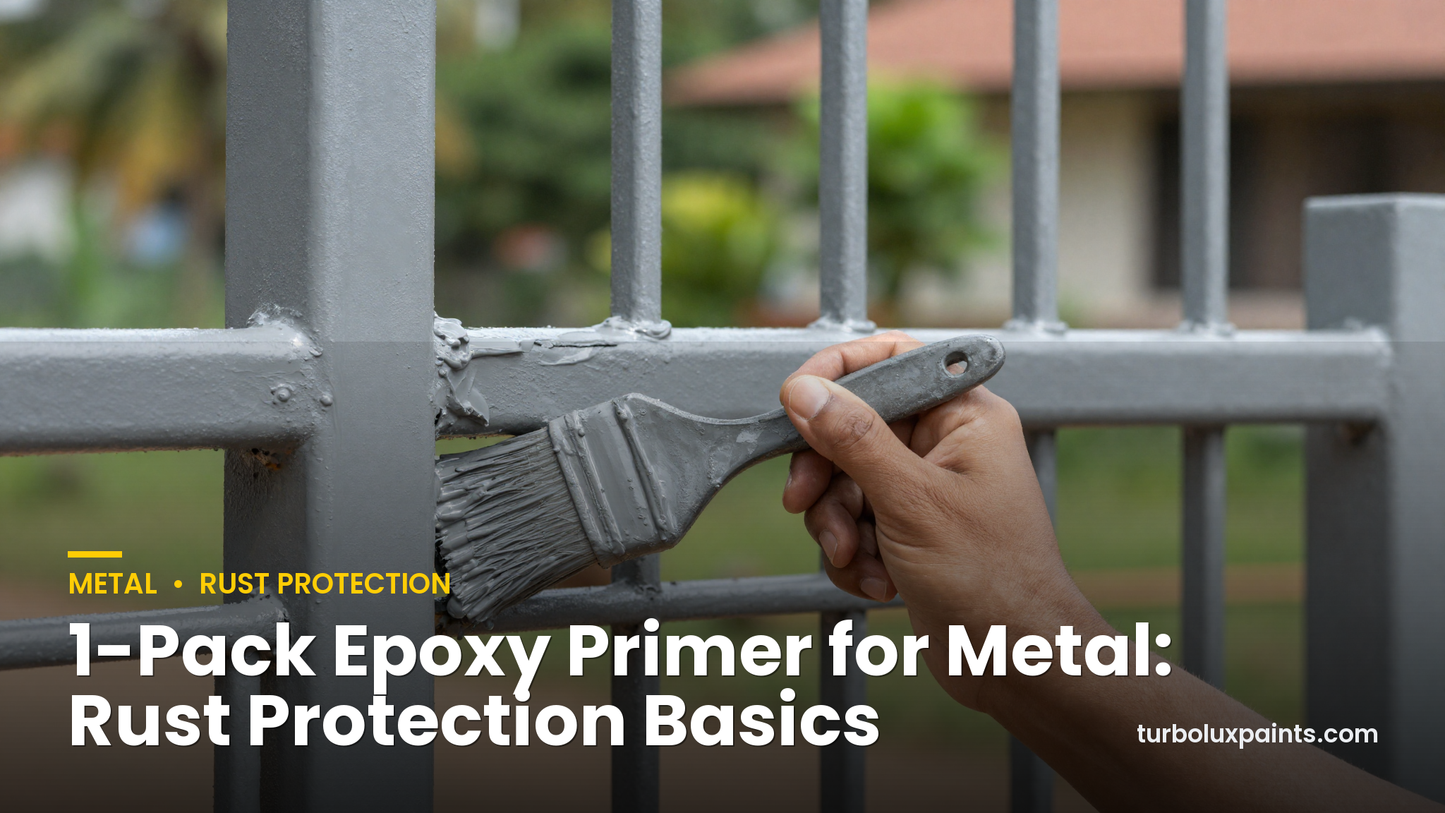 Hand applying grey epoxy primer with a brush onto a rusty metal gate outside a Kerala home